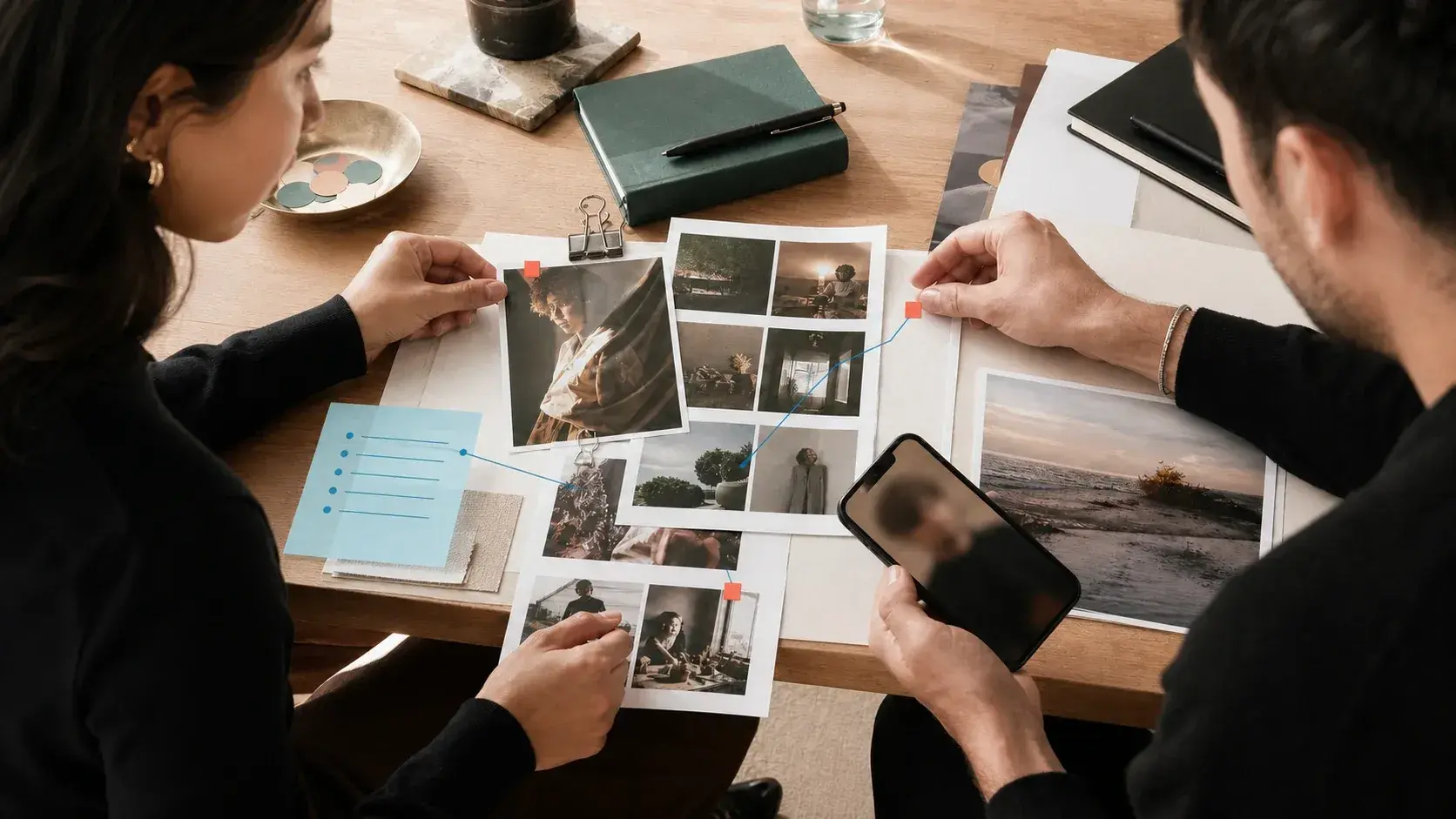 Two creator strategists reviewing candidate photographs, evidence notes and marked decision paths